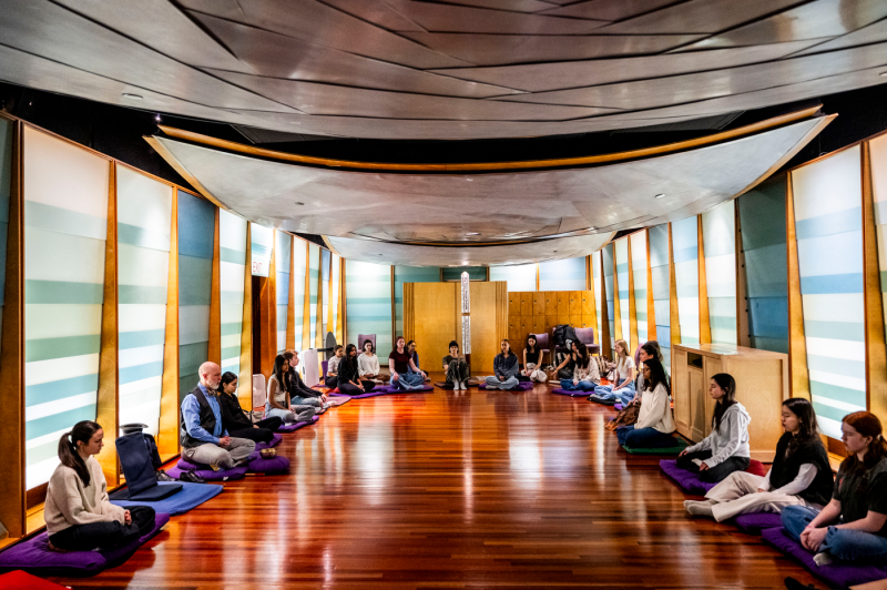 A group of students, faculty and staff sit and meditate in the sacred space of Northeastern University.