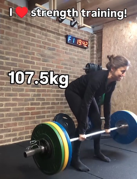 A woman performs a deadlift with a 107.5 kg barbell.