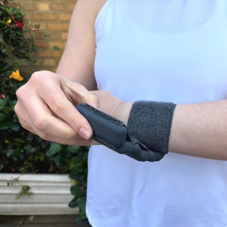 A woman wearing a white shirt and a black ball bangle around her wrist.