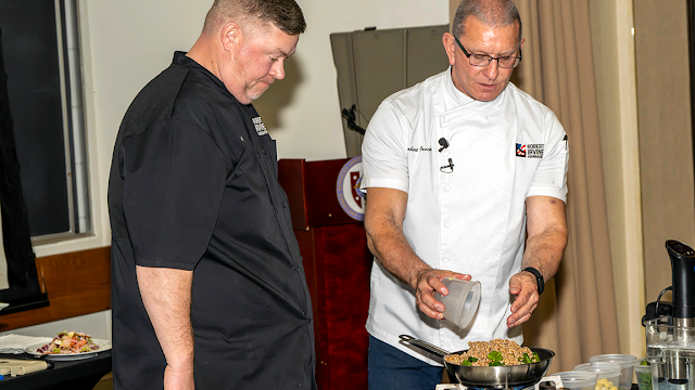 Celebrity chef Robert Irwin (right) and his sous chef Shane Cash (left) demonstrate how to prepare healthy meals for Uniformed Services University students and faculty, March 13, 2026. (Photo credit: Tom Balfour, USU)