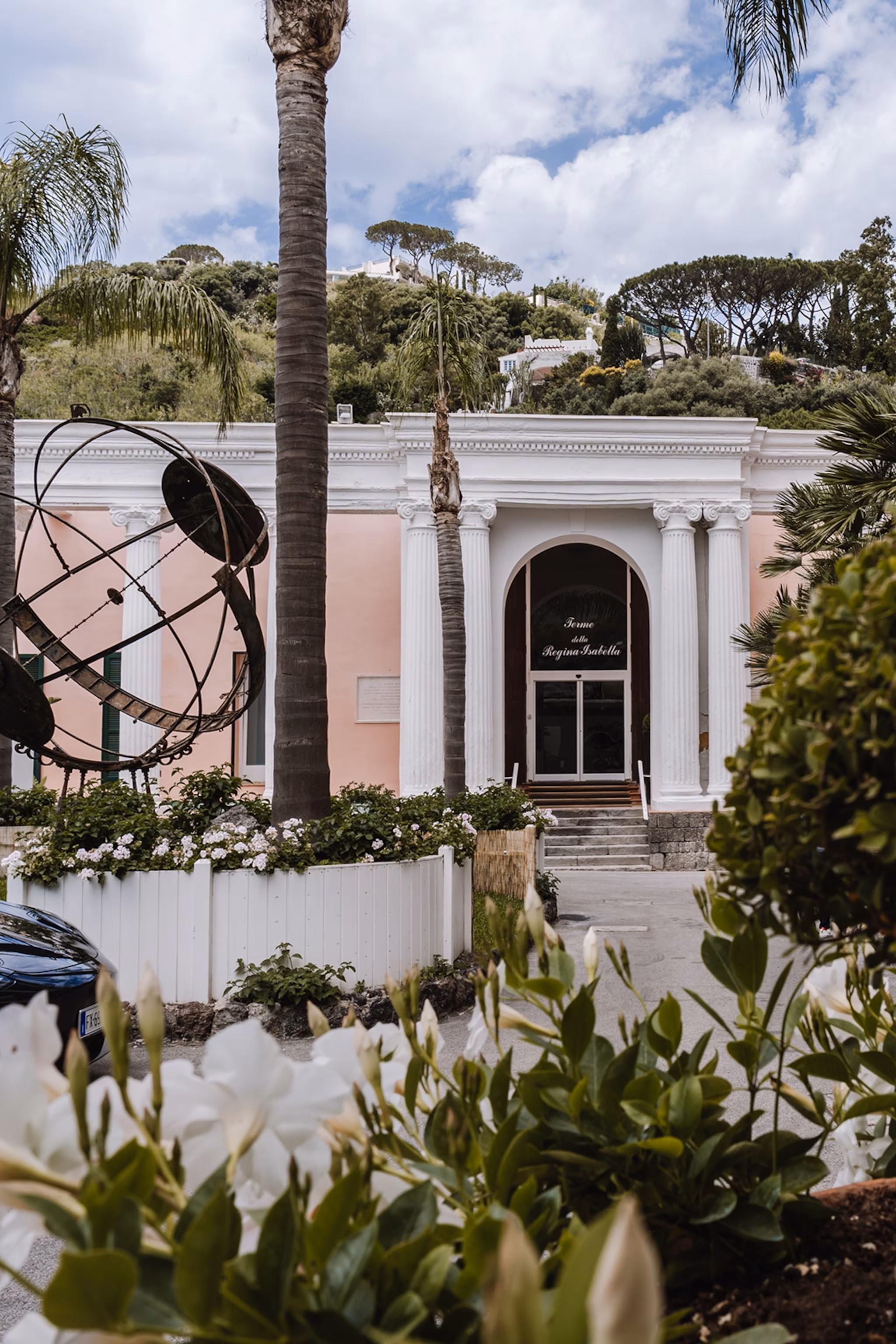 Spa hotel entrance with calligraphy and bronze globe statue outside.