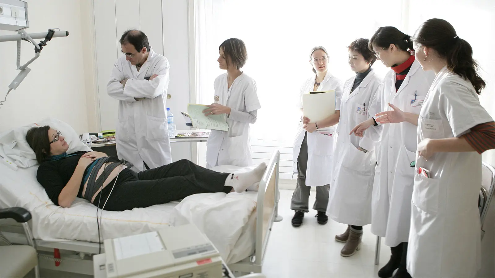 A photo of medical students gathered around the hospital bed of a pregnant woman.