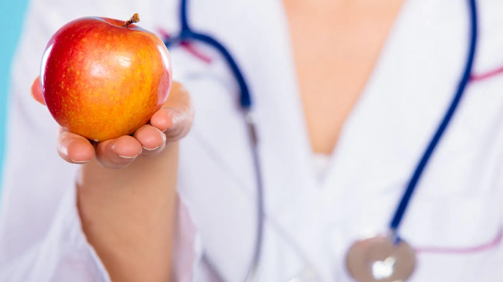 A photo of a female physician holding an apple.