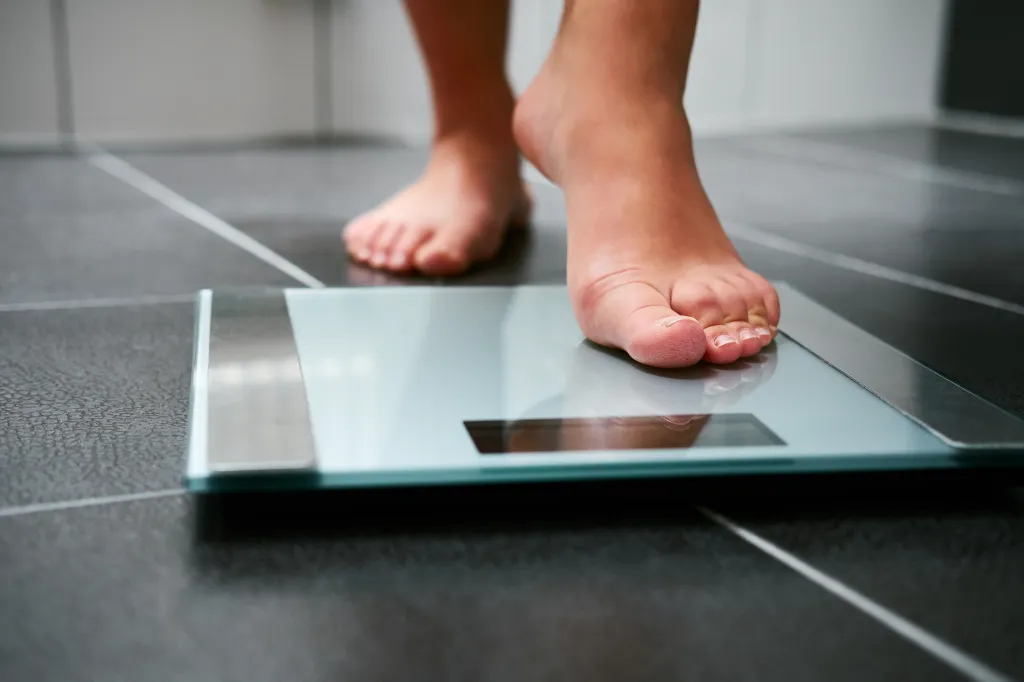 A person's bare feet are standing on a bathroom scale.